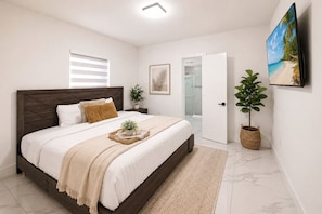 A bedroom with a bed, bedside table, and a TV mounted on the wall. - Modern Retreat • BBQ • Near South Beach & MIA (Miami)