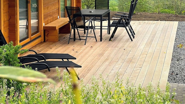 A wooden cabin with a deck, a table, and chairs. - 42 - Bungalow Chalet "Joscha" (Daun)