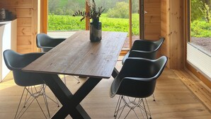 A wooden interior with a large table, black chairs, and a hanging light fixture.