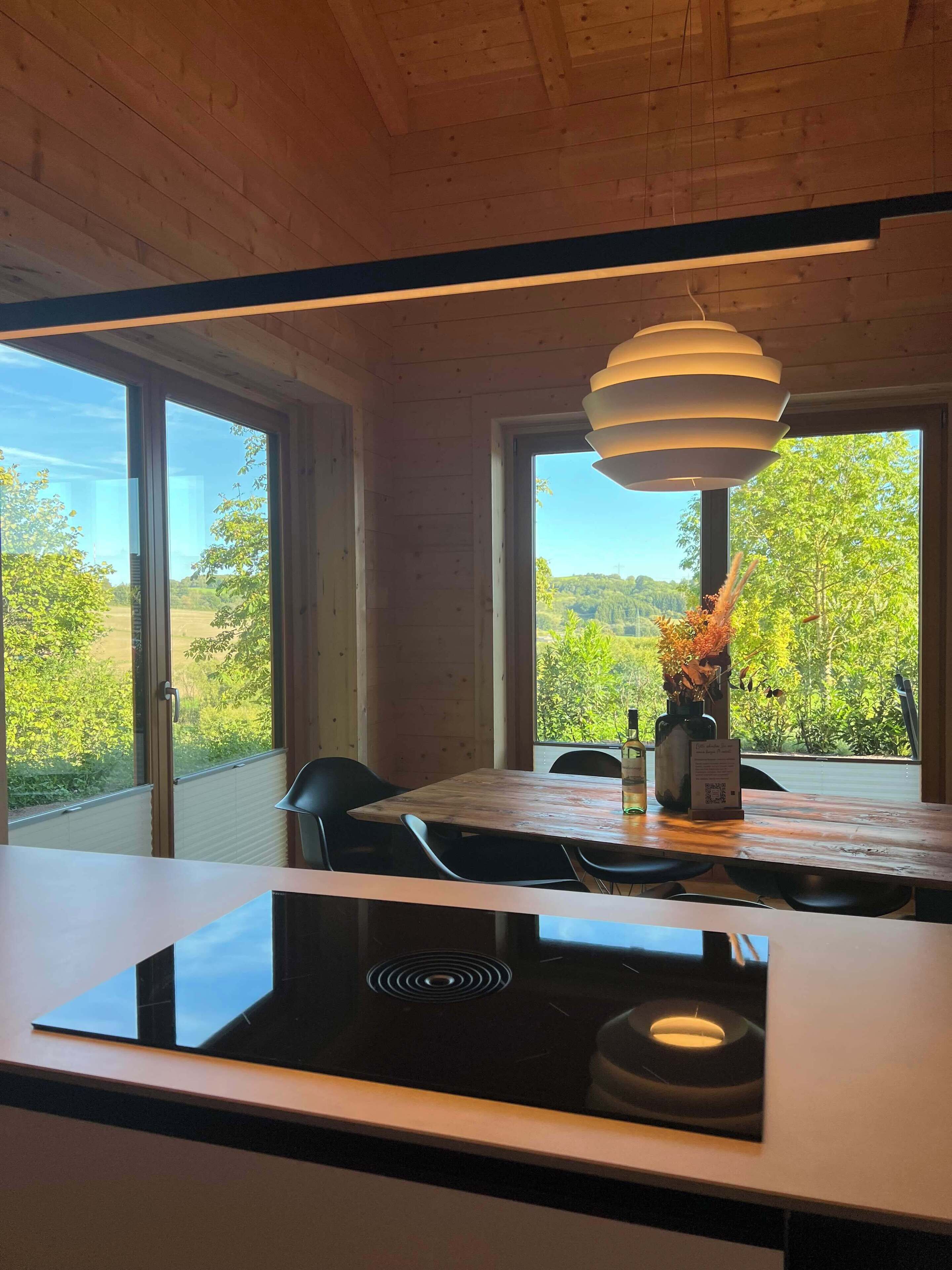Une cuisine moderne dotée d’un îlot central, de grandes fenêtres et d’un luminaire suspendu.