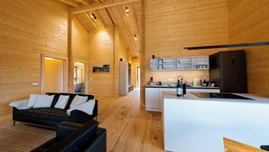 A spacious log cabin interior with a living area, kitchen, and dining space.