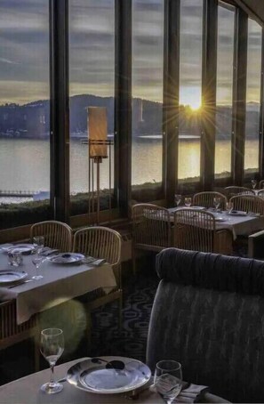 Enjoy a serene dining experience with a scenic view of the water and distant hills.
