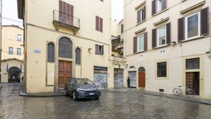 A cobblestone street in a historic town with a parked car and a bicycle.