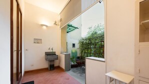 A narrow hallway with a sink, a small table, and a view of a garden through a glass door. - San Zanobi 33 - One Bedroom Apartment, Sleeps 2 (Firenze)