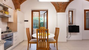 A modern kitchen with a dining area, featuring a brick ceiling, white walls, and a large window. - San Zanobi 33 - One Bedroom Apartment, Sleeps 2 (Firenze)
