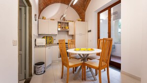 A kitchen with white cabinets, a brick ceiling, and a round dining table with four chairs. - San Zanobi 33 - One Bedroom Apartment, Sleeps 2 (Firenze)