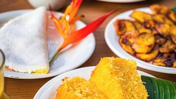 A table with various dishes, including a banana leaf dish, a plate with fried items, and a bowl with a yellow condiment.