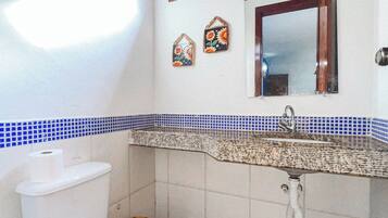 Une salle de bain avec des toilettes, un lavabo et une fenêtre située au-dessus du miroir.