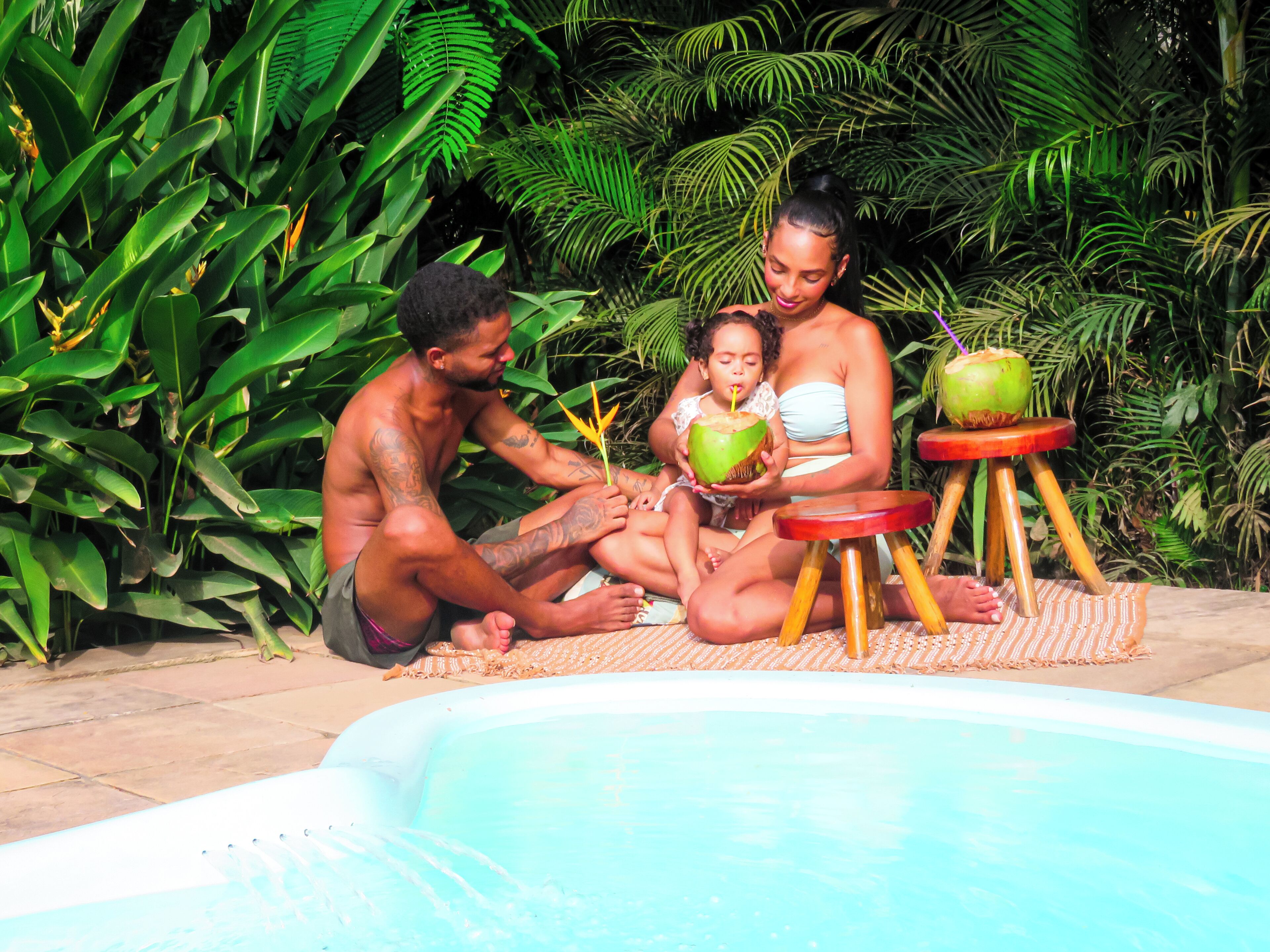 Una familia junto a una piscina en un entorno tropical.