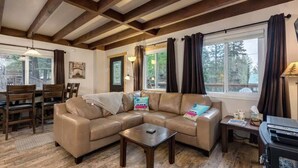Un salon chaleureux avec un canapé en cuir marron, un plancher en bois et des poutres apparentes en bois au plafond.