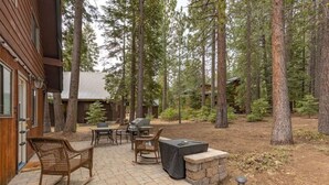 Une terrasse avec des meubles d’extérieur, un barbecue et un mur en pierre.