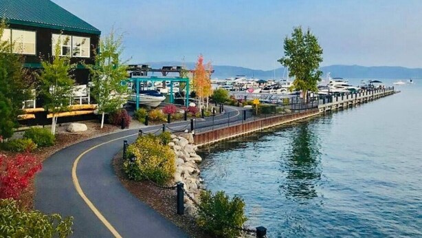 Une propriété située au bord de l’eau, dotée d’une promenade pavée, d’un port de plaisance et d’un bâtiment surmonté d’un toit végétalisé.