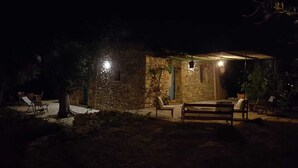 Un edificio de piedra con un patio techado, mesas al aire libre y luces colgantes.