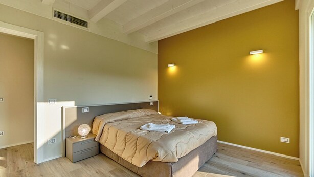Une chambre à coucher comprenant un lit, une table de chevet et un luminaire fixé au mur.