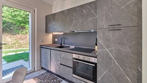 Une cuisine moderne avec des meubles de couleur gris marbré, un robinet noir et des appareils électroménagers en acier inoxydable.