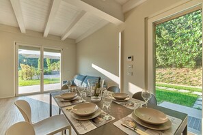Un coin repas avec une table dressée pour quatre personnes, un canapé et une vue sur un jardin.