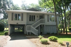 Stroll up the grand staircase to a covered entryway, surrounded by lush trees and a beautifully manicured lawn.