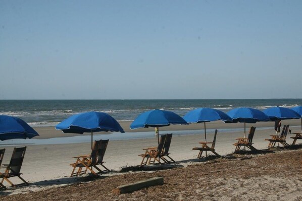 Relax by the ocean with comfortable beach chairs and shaded umbrellas.