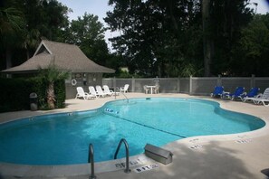 Relax by the pool surrounded by lush greenery and lounge chairs on the concrete deck.