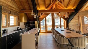 A spacious kitchen with a large island, wooden beams, and a dining area with chairs.