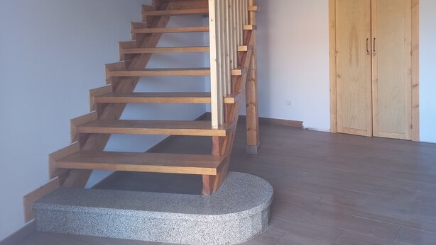 Eine Holztreppe mit einem Granitpodest, einer Holztür und einem Oberlicht im Hintergrund.