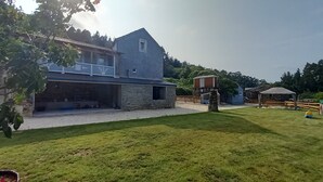 Ein Haus mit einer Steinaußenwand, einem Balkon und einer kleinen Holzkonstruktion im Hof.