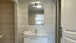 Une salle de bain moderne avec un meuble-lavabo blanc, un miroir et un espace douche.