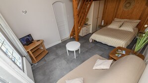 Une chambre à coucher comprenant un lit, un canapé, une petite table, une chaise, un escalier en bois et une fenêtre.