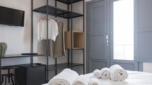 Une chambre d’hôtel équipée d’un lit, d’un téléviseur fixé au mur, d’une armoire et d’une fenêtre laissant entrer la lumière du jour.