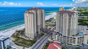 A high-rise hotel with multiple floors, a beach view, and a parking area. - Beachfront Bliss! 4th-Floor Condo 2BR/2BA Sleeps 8! Steps from the water! (Panama City Beach)