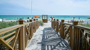 A wooden boardwalk leading to a beach with umbrellas and a lifeguard tower. - Beachfront Bliss! 4th-Floor Condo 2BR/2BA Sleeps 8! Steps from the water! (Panama City Beach)