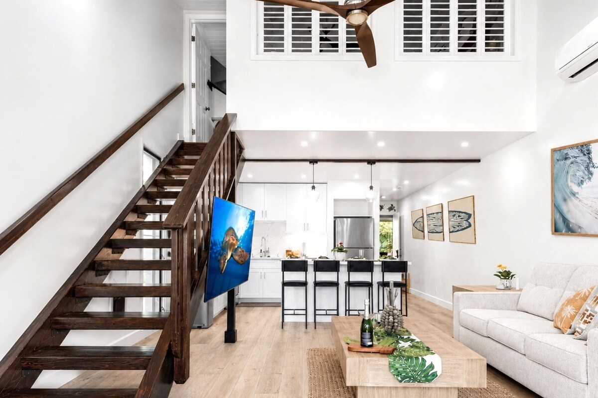 A modern interior with a wooden staircase, a kitchen area, and a living room with a sofa.