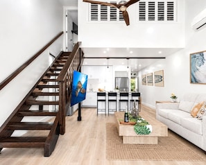 A modern interior with a wooden staircase, a kitchen area, and a living room with a sofa.
