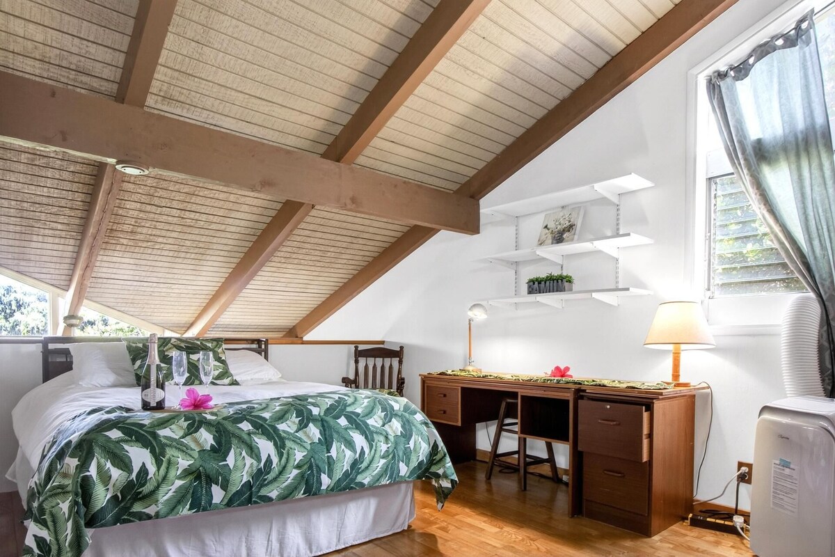 Un dormitorio con una cama, un escritorio y una silla. Hay una ventana con cortinas y una estantería con plantas.