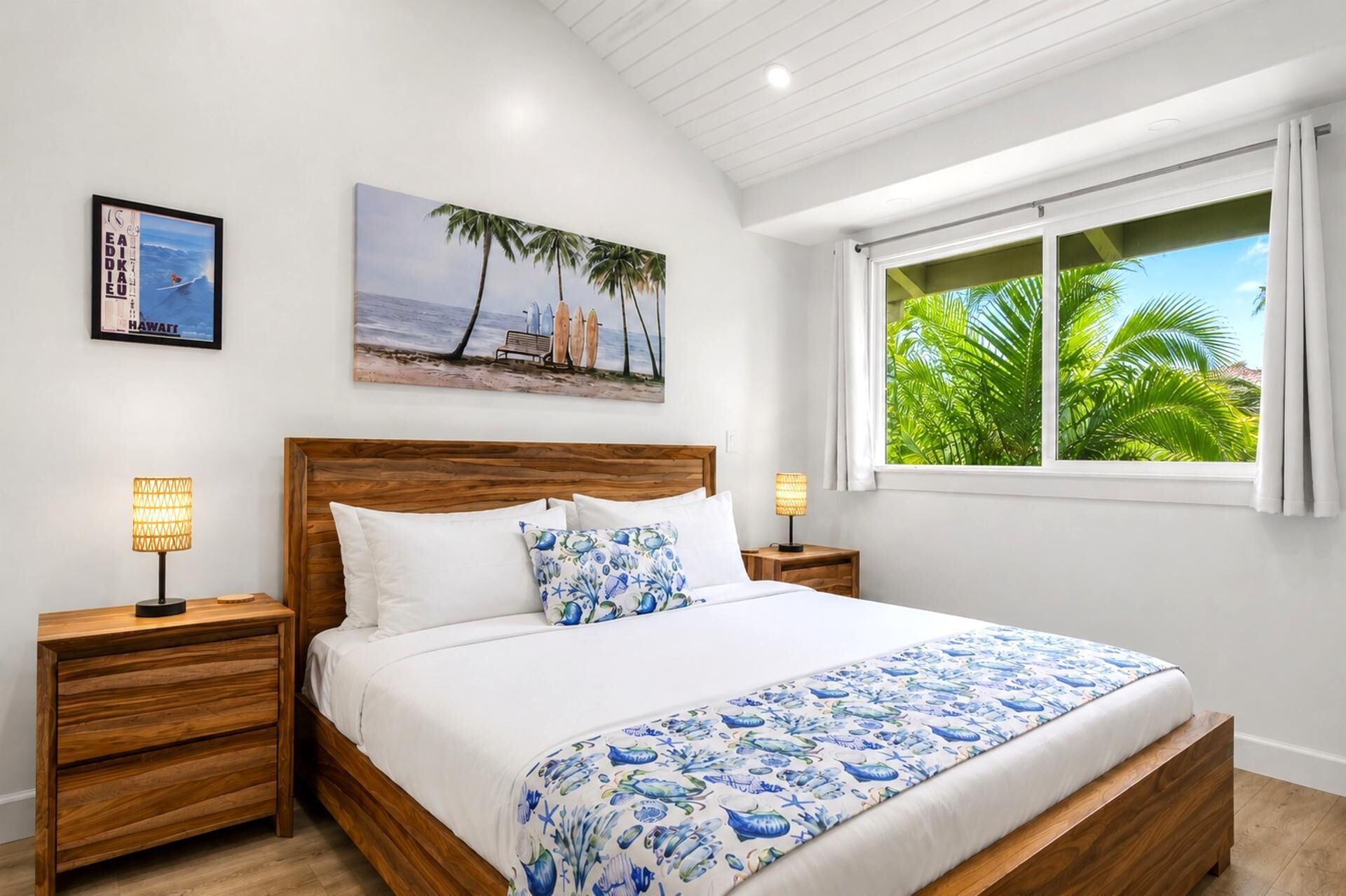 A bedroom with a wooden bed, white bedding, a beach-themed painting, and a window with a view of palm trees.