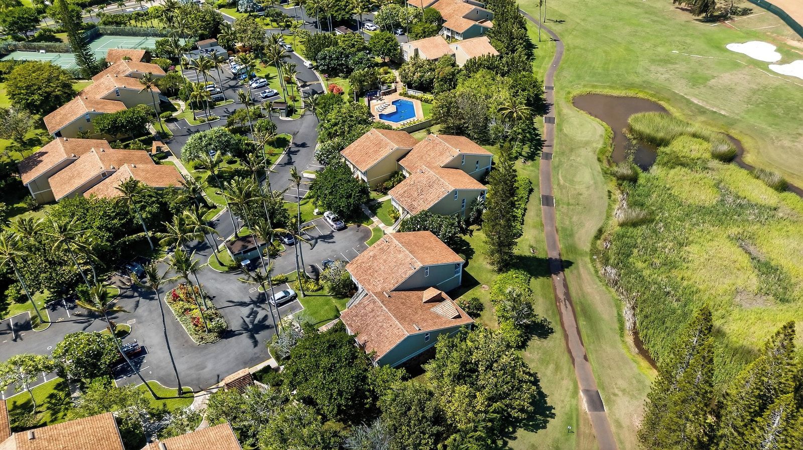 Vue aérienne d’un quartier résidentiel avec des maisons, une piscine et un terrain de golf.