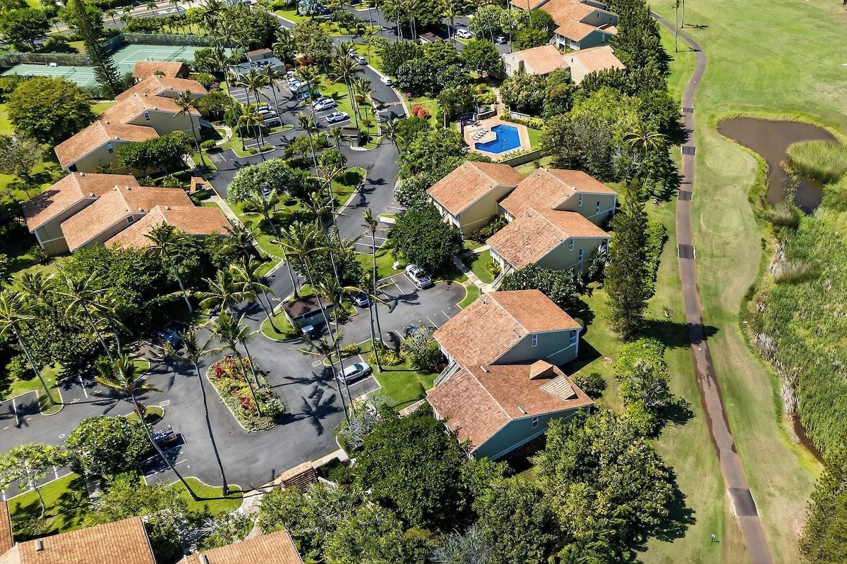 An aerial view of a residential area with houses, a swimming pool, and a golf course.