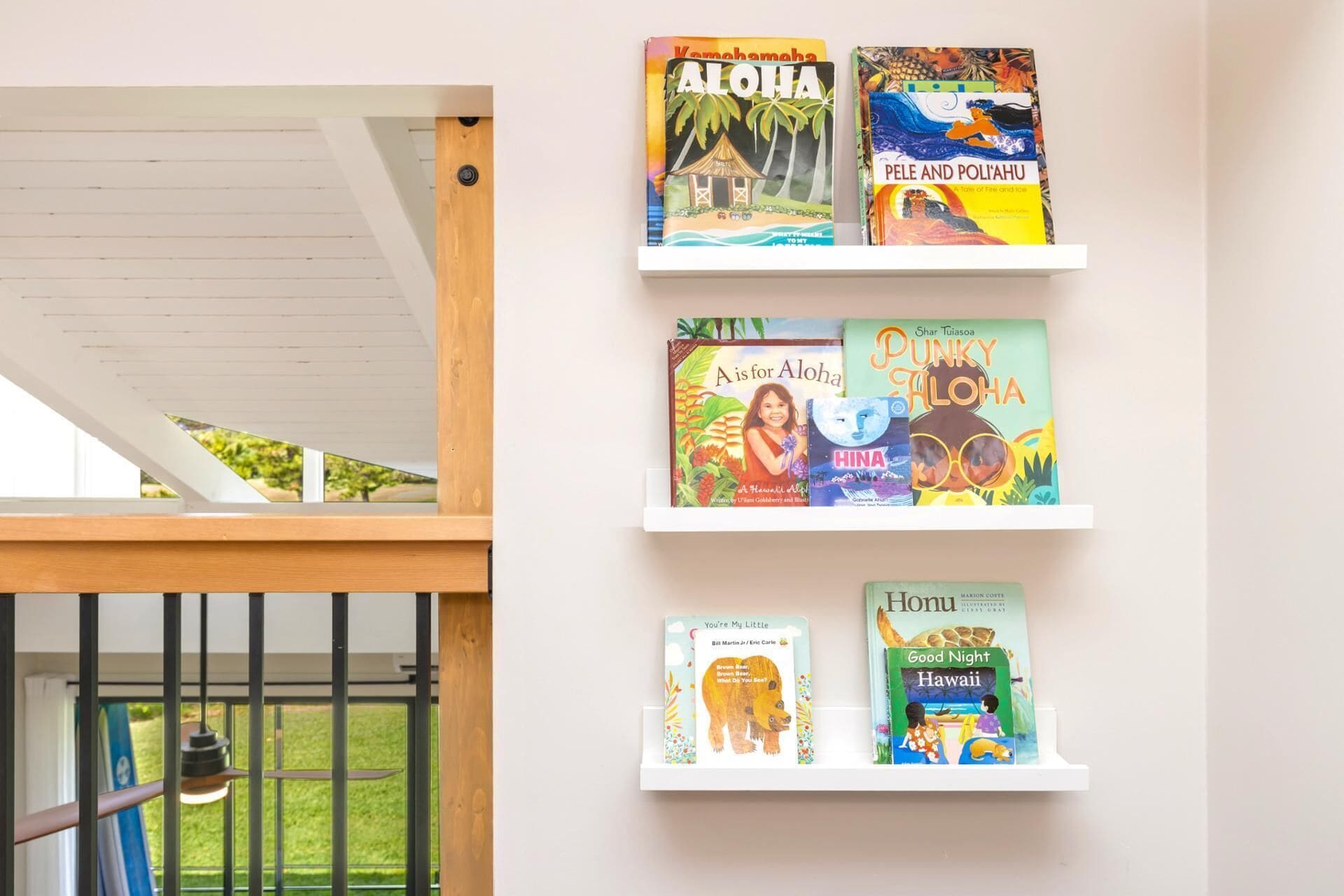 A wall with four white shelves displaying children's books.