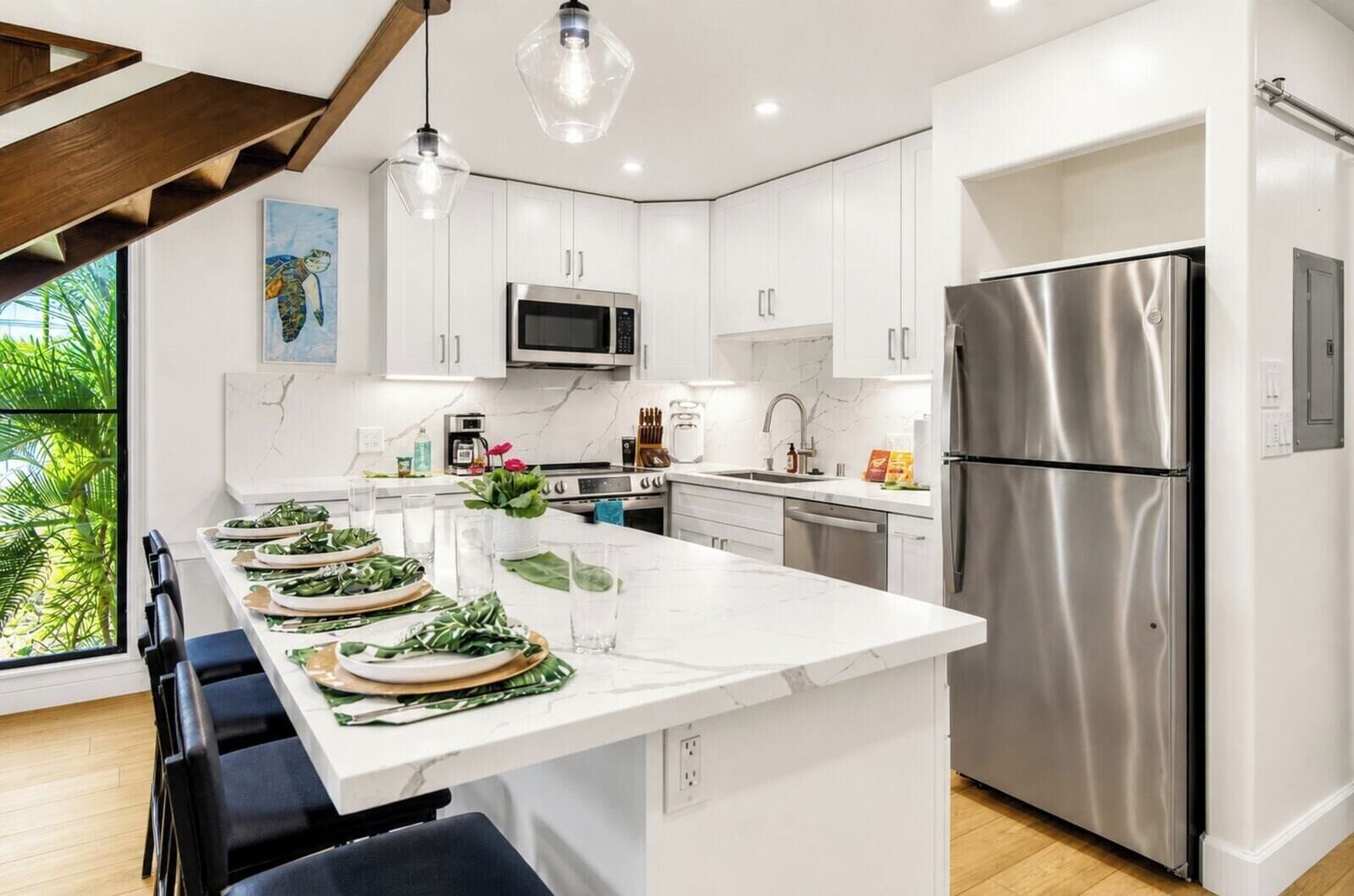 A modern kitchen with white cabinets, stainless steel appliances, and a large island with seating.