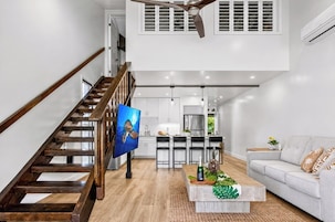 A spacious living area with a wooden staircase, a dining area, and a kitchen.