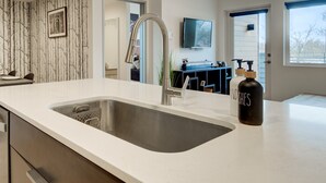 Eine moderne Küche mit Spüle aus Edelstahl, einer weißen Arbeitsplatte und einer schwarzen Handseifenflasche.