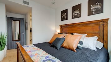 Een slaapkamer met een houten hoofdbord, een bed met meerdere kussens, een kleurrijke sprei en drie kunstwerken met eekhoornmotieven.