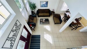 A spacious living area with a large window, a sofa set, a coffee table, and a dining table with chairs.