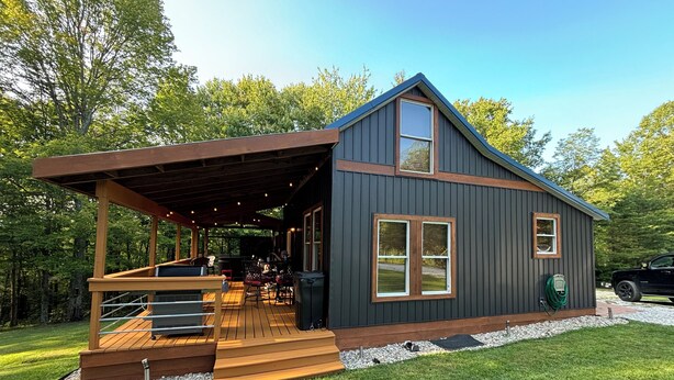 A modern cabin with a covered deck, large windows, and a garage. - Cabin in Hocking Hills with Hot Tub, Fire Pit and Covered Back Deck. (South Bloomingville)