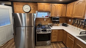 A kitchen with wooden cabinets, a stainless steel refrigerator, a stove, and a microwave. - Cabin in Hocking Hills with Hot Tub, Fire Pit and Covered Back Deck. (South Bloomingville)