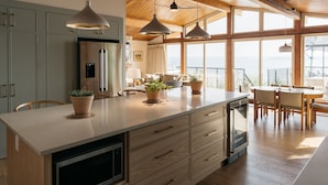 Une cuisine moderne dotée d’un grand îlot central, de meubles en bois et de luminaires suspendus.