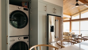 Une buanderie équipée d’un lave-linge et d’un sèche-linge, d’un réfrigérateur en acier inoxydable, de chaises en bois et d’une table.