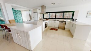 A modern kitchen with white cabinetry, a central island, a built-in oven, and a dishwasher. - Villa Lili (El Perelló)