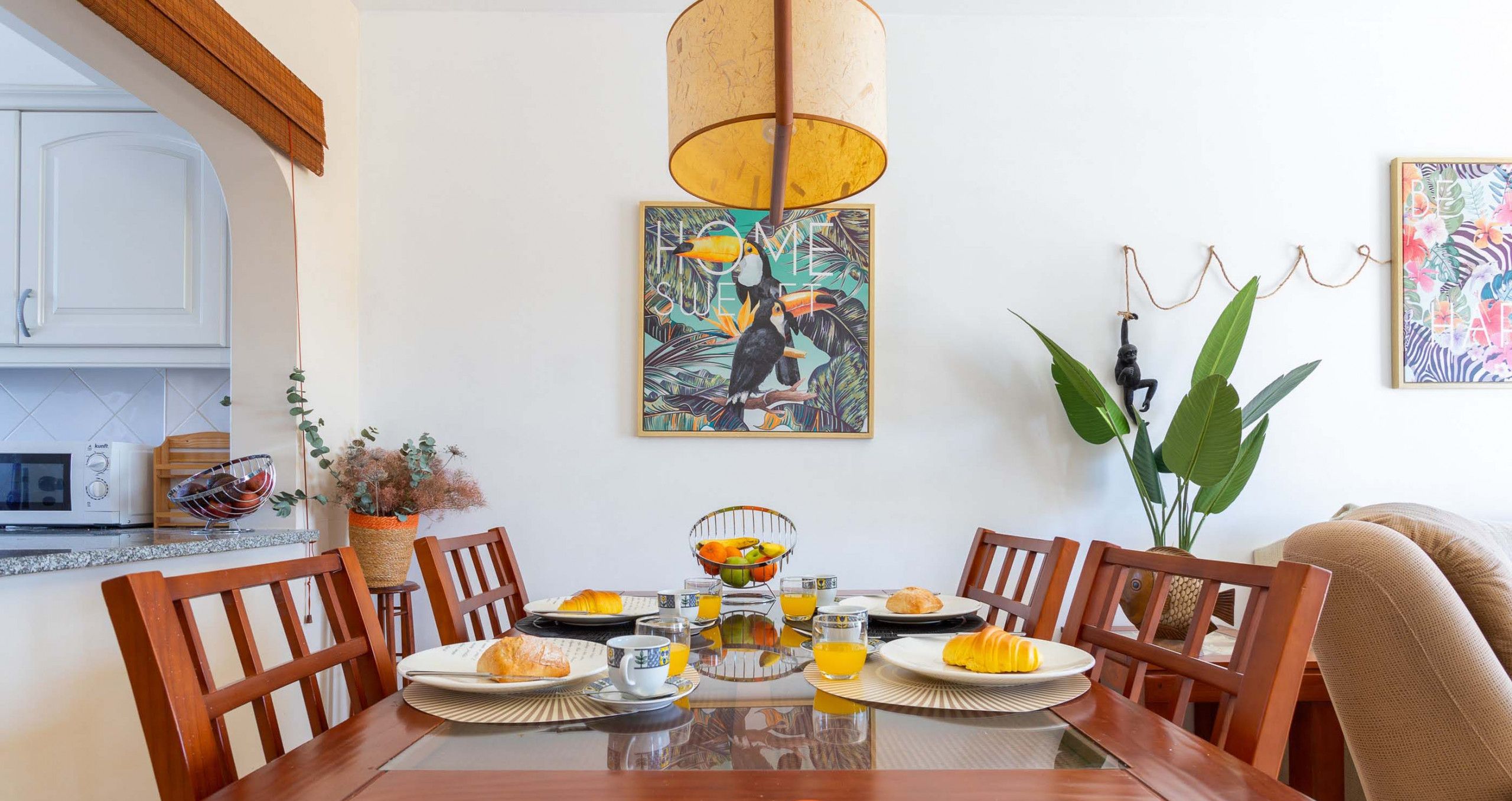 A dining table set with plates, croissants, and a fruit bowl.