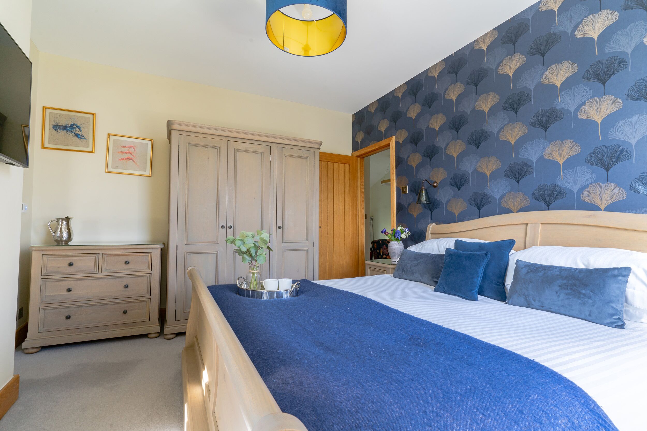 Un dormitorio con una cama, un aparador, un espejo y una pared con diseño de hojas.